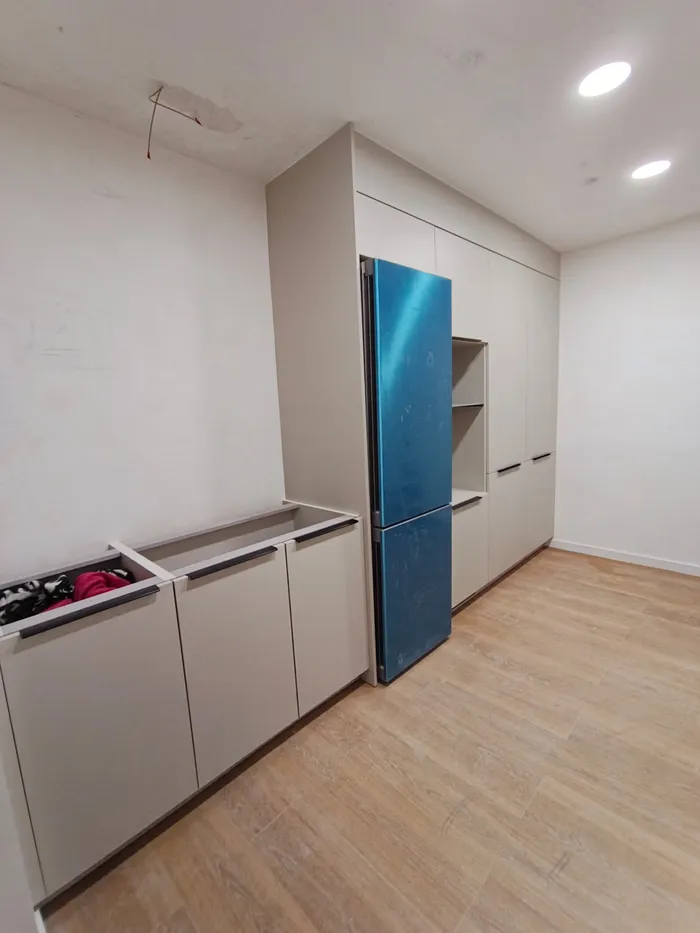 Instalación de armario de cocina blanco junto a nevera en pasillo