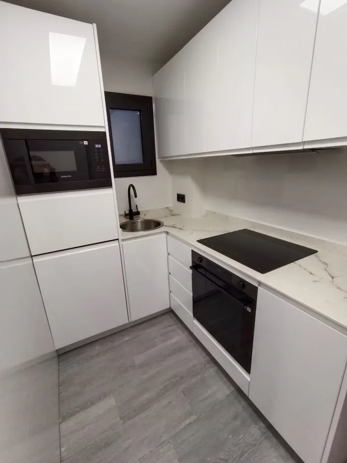 Cocina blanca compacta con encimera de mármol y horno integrado